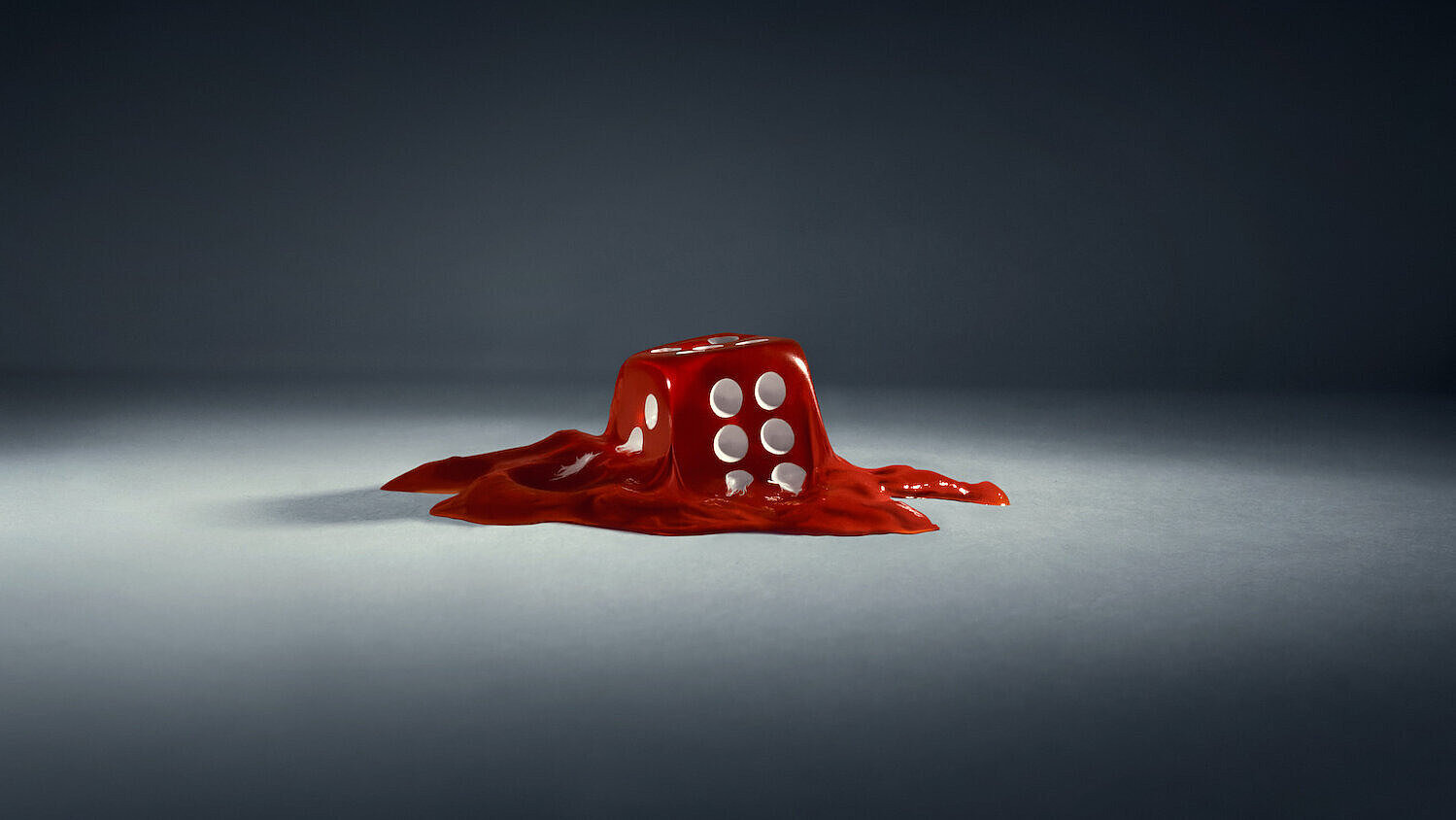 Ein roter Würfel schmilzt vor einem dunklen Hintergrund. 